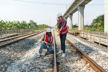 Rail transportation engineer in safety vest and hardhat check the neatness of the railway track...