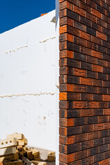 Next to a pile of bricks, a brick wall is under construction. The materials being used include...