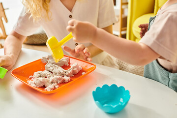 A toddler enjoys a meal at a table guided by her mother, utilizing the Montessori method of education.
