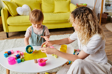 A curly mother engages with her toddler daughter in Montessori play, exploring toys together in a...