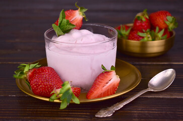 Organic strawberry ice cream in a glass on a dark wooden background.
