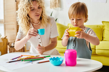A curly-haired mother and her toddler daughter sit at a table, engrossed in Montessori learning...