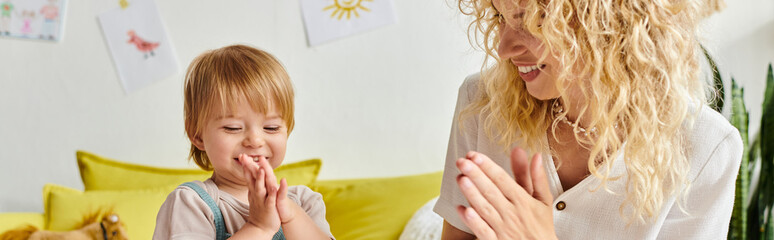 A curly-haired mother and her toddler daughter engage in Montessori activities on a cozy couch at...