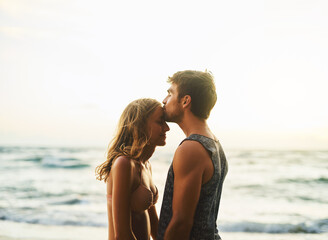 Man, woman and forehead kiss at beach for love, travel and vacation in nature for summer sunset....