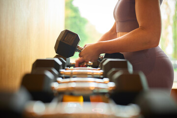 Close Up Of Woman Exercising Picking Up Weights In Gym