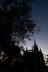 Natchez, Mississippi, USA - April 21, 2024: Twilight silhouettes a tree and a historic church of downtown Natchez.