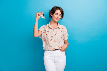 Portrait of pretty positive girl hand hold demonstrate new apartment key isolated on blue color...