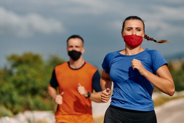 Couple running in nature at morning wearing protective face masks