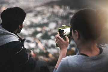Couple, people and hike with smartphone for city view photography in mountain, relax and bonding in...