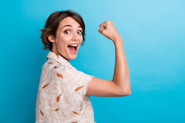 Profile portrait of overjoyed satisfied girl raise fist shout yes empty space isolated on blue...