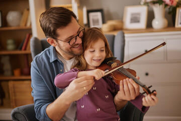Father teaching his little daughter to play violin and smiling © Stockphotodirectors