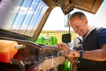 Close Up Of Mature Male Farm Worker Fixing Machinery