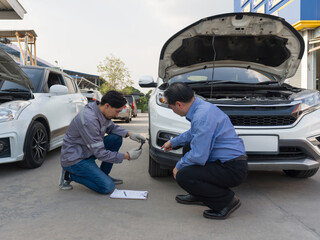 Two individual inspect damage on a vehicle. Car’s owner pointing at a dent on the bumper of the...