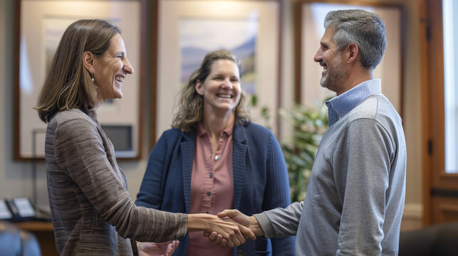 A middle-aged couple smiles and shakes hands with a financial planner after a successful meeting about their retirement plans. The couple appears relieved and confident, while the planner beams with