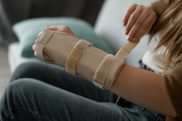 woman adjusts her orthosis. Hand stiffness when using orthosis, problems with the hands, pain in...