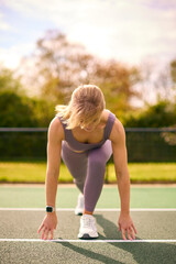 Woman Wearing Fitness Clothing Stretching Before Start Of Race Outdoors