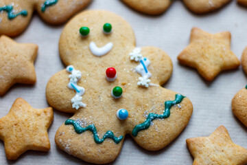 A small decorated Christmas gingerbread man surrounded by other sweets. Christmas baking