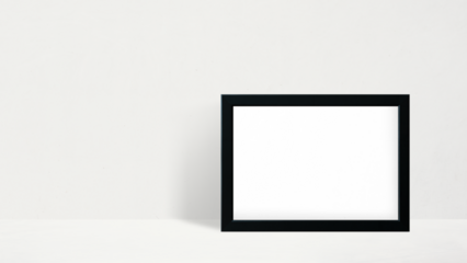 Black picture frame mockup leaning against a white wall