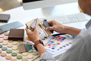 Experienced Interior designer holding color samples working on new design project at office