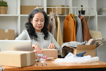 Mature woman small business owner preparing products for deliver to customers. E-commerce concept