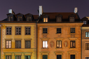 Night low angle view of traditional low-rise roof-tiled houses with facade decorations in the Old Town Market Place (Rynek Starego Miastra), Warsaw, Poland