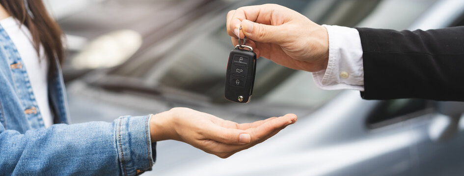 transportation rental automotive business concept. Close up hands of rental auto agent giving car remote key to client to travel sightseeing.
