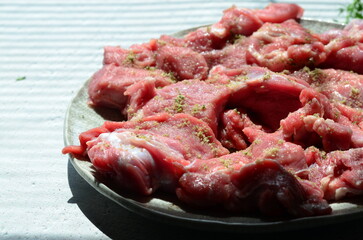 Thinly sliced fresh veal, carefully prepared and seasoned, ready for cooking. The raw meat is displayed on a light background, highlighting its texture and quality