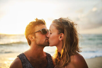 Man, woman and kiss at beach for sunset, travel and vacation to island in summer for love. Happy,...