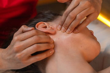 Close-up of the hands of a masseur doing facial massage to a young brunette woman in a spa salon. Concept of health and beauty