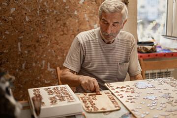 Dementia prevention. Elderly man hands doing jigsaw puzzle at home