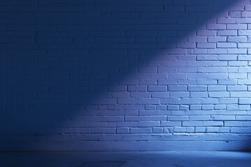 Brick wall illuminated by an upward beam of light creating a soft gradient effect and emphasizing the brick texture