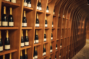 Big wooden shelf with sparkling wines in cellar, interior photography. Big assortment of champagne. 