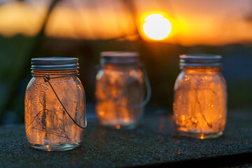 Three solar-charged lamps with garlands inside in drops after the rain stand on the terrace in the...