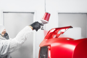 Naklejka premium Man sprays red dye on the elements of the vehicle.