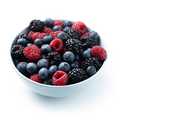 Fresh assortment berries in bowl isolated on white background. Copy space