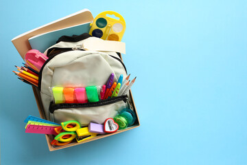 Cardboard box with backpack full of brightly colored school supplies. Back to school donation drive...