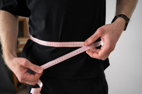 Unrecognized man measuring waist with a tape measure