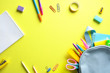 Back to school concept with colorful stationery scattered on a bright yellow background. Flat lay, top view, copy space.