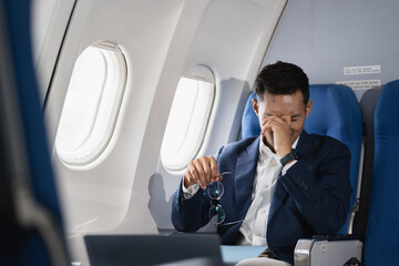 Tired asian man with headache feeling sick while sitting in the airplane , Passengers near the...