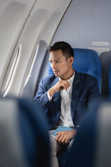 Tired asian man with headache feeling sick while sitting in the airplane , Passengers near the window.