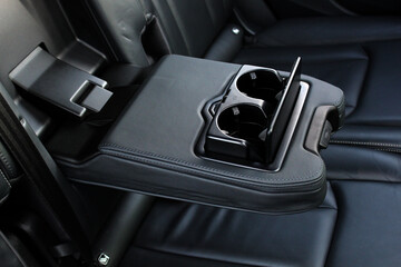 Leather rear seat armrest with cup holders in a new modern car. Car passenger back rear seats...