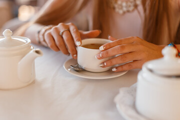 young girl sits in a cafe and drinks delicious tea, close-up