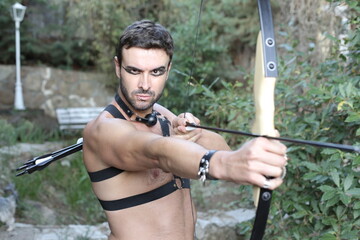 Sexy male archer aiming a target 