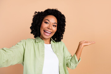 Portrait of pretty young lady take selfie hold empty space wear green shirt isolated on beige color background