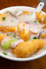 angle view fish slices and pork porridge with deep-fried Chinese donuts at vertical composition