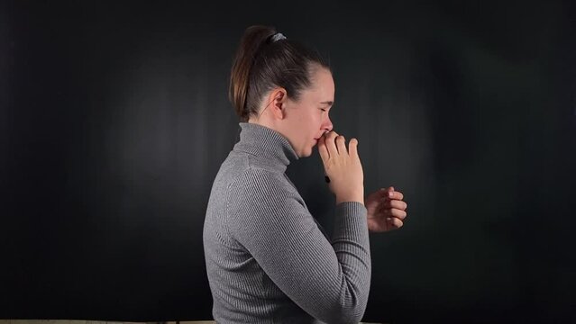 Portrait a young woman wearing gray uses a nasal spray to alleviate a runny nose amidst a black backdrop. Addressing symptoms of the flu, cold, virus. She undergoes therapy to combat seasonal illness
