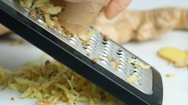 The process of grinding fresh ginger root on a grater, slow motion.