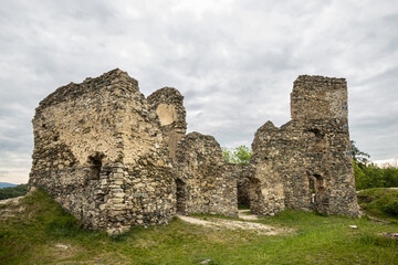 Remains of walls of medieval castle on hill under cloudy sky