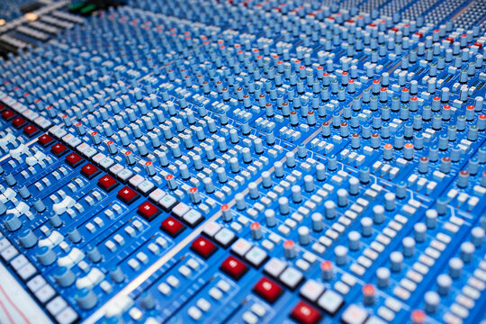 This is an image of a detailed sound mixing console with numerous knobs, sliders, and buttons used for audio production.