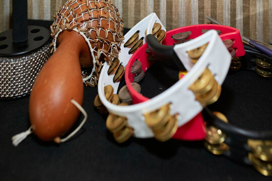 A collection of musical percussion instruments, including a shekere, tambourines with metal jingles, and possibly other hidden instruments.